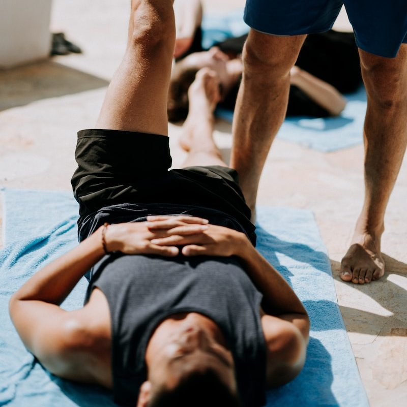 man lying on floor near man standing holding his leg